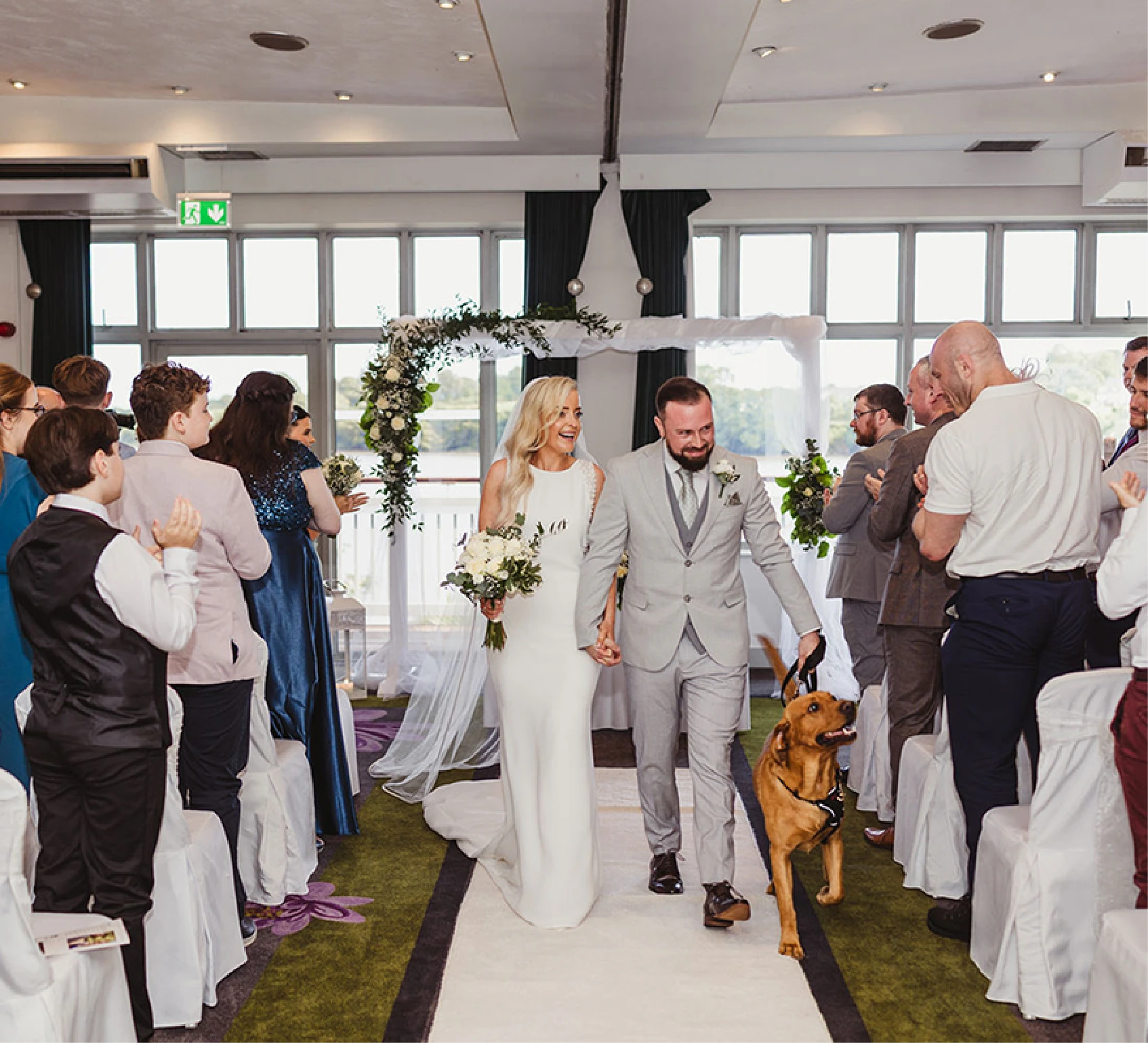 Bride and groom walking back down the aisle with their dog at a Ferrycarrig ceremony in Wexford