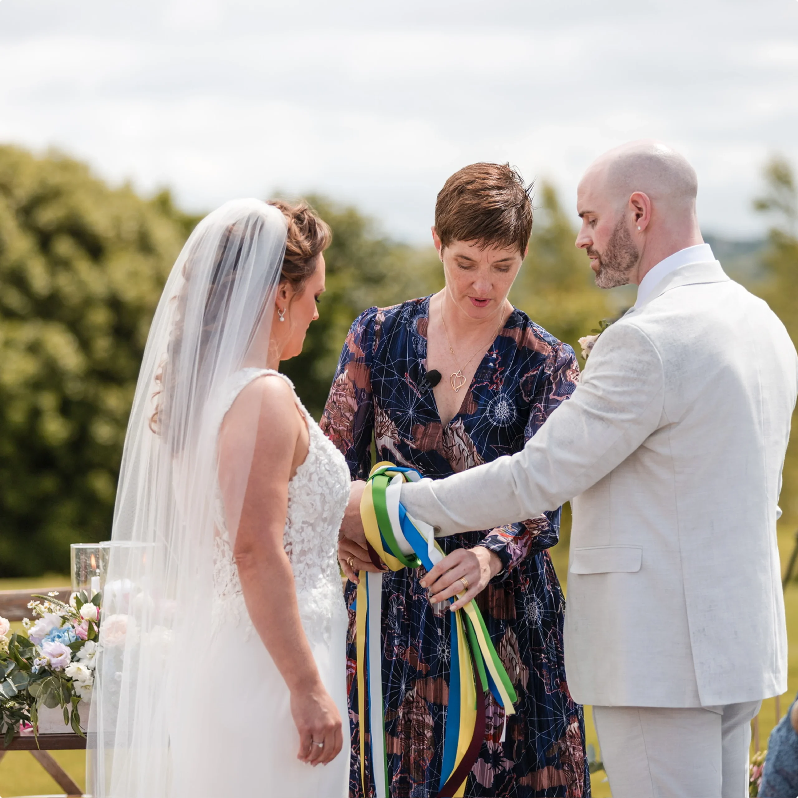 Rosemary Hartigan tying handfasting ribbons around the bride and groom’s hands