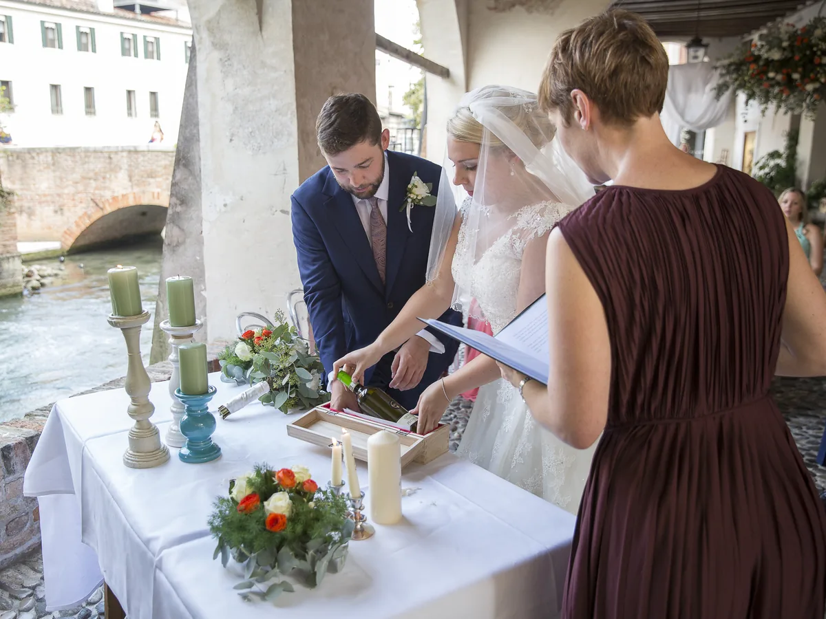 Rosemary Hartigan with Emily and Matt as they place a bottle of wine into their wine box during their ceremony in Treviso, Italy